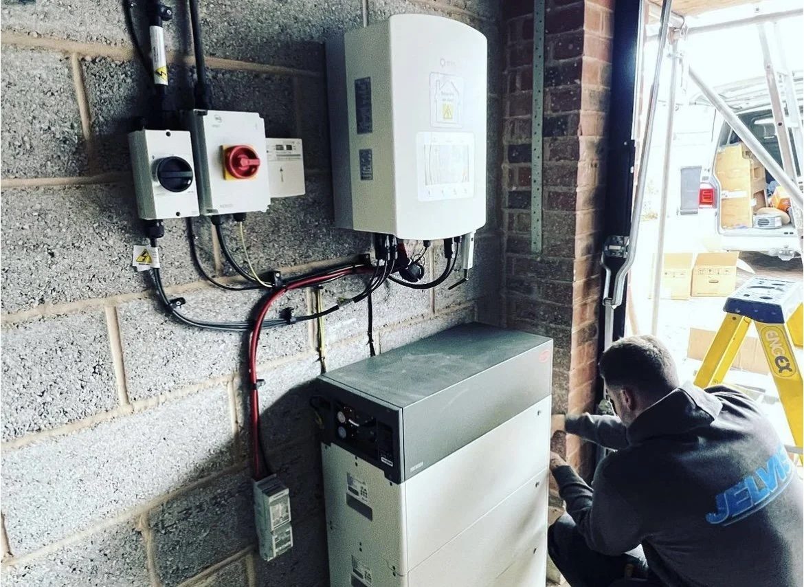 An engineer working beside inverter and battery equipment.