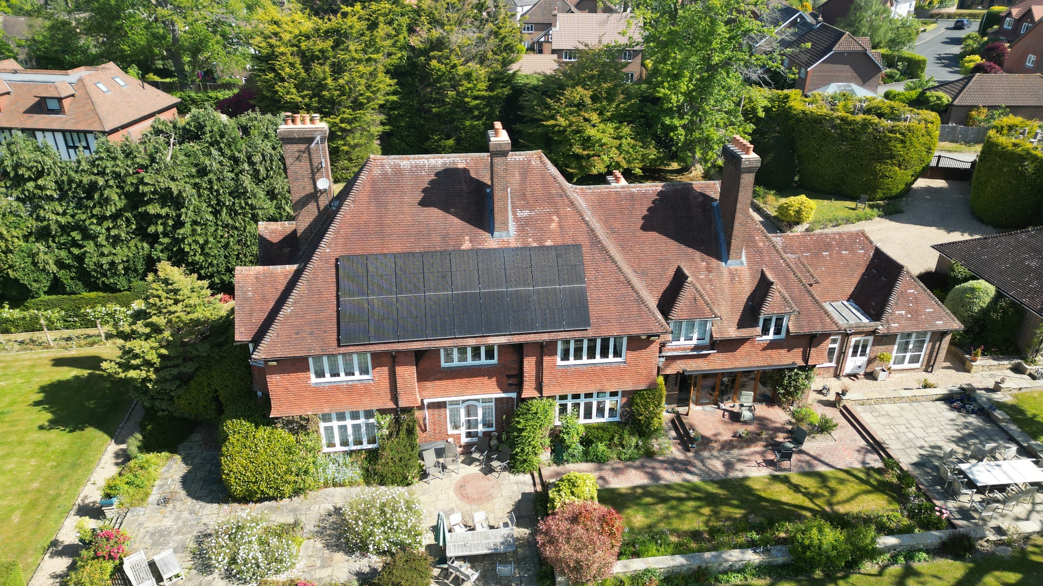 Aerial view of an all-black array on a tiled house roof.