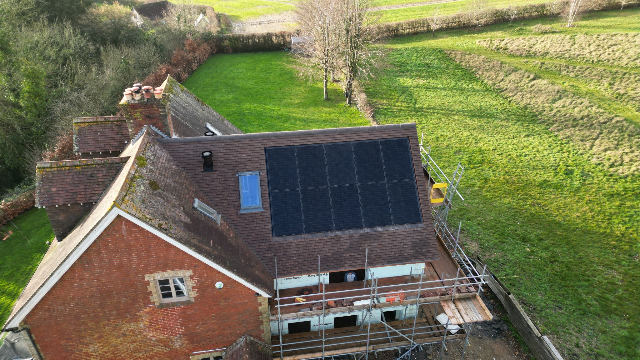 An integrated solar PV array beside a rooflight, with scaffolding still in place.